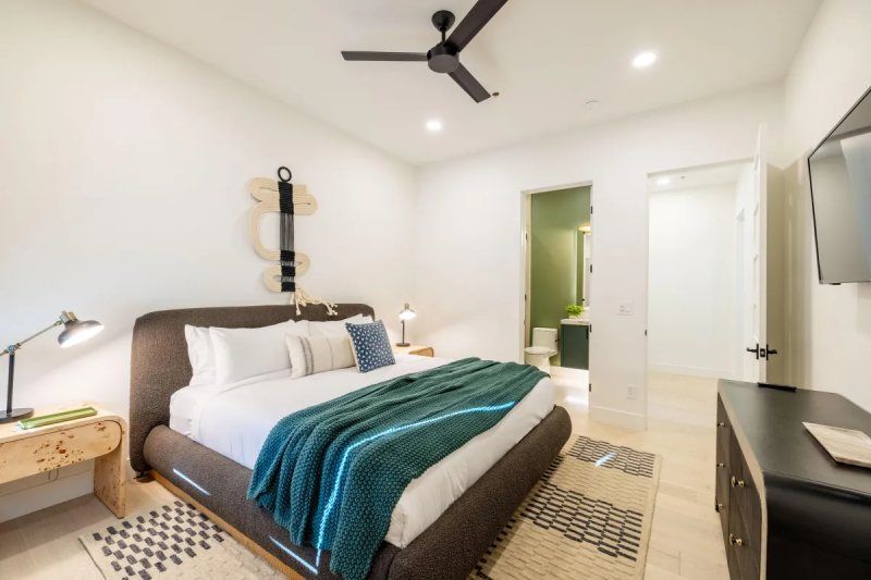 Bedroom with a bed, dresser, and rug; an open doorway leads to a bathroom.