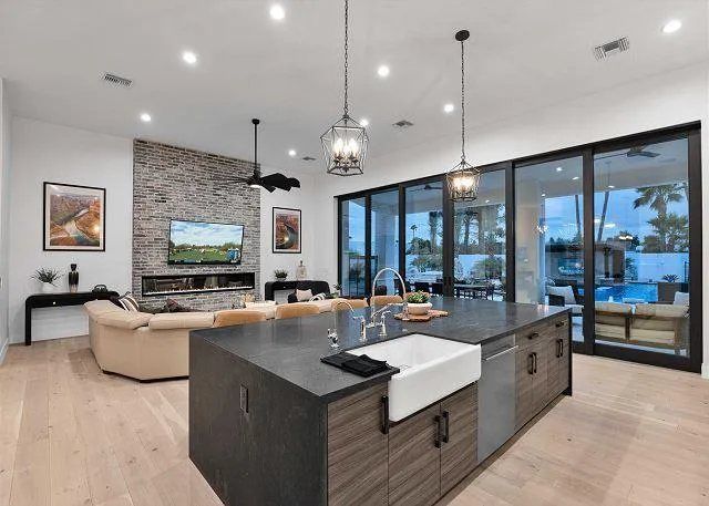 Modern kitchen with island, adjacent to living room, large glass doors to pool.