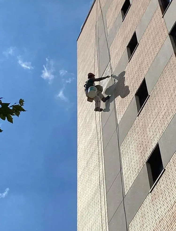 Un hombre está subiendo por el costado de un edificio alto.