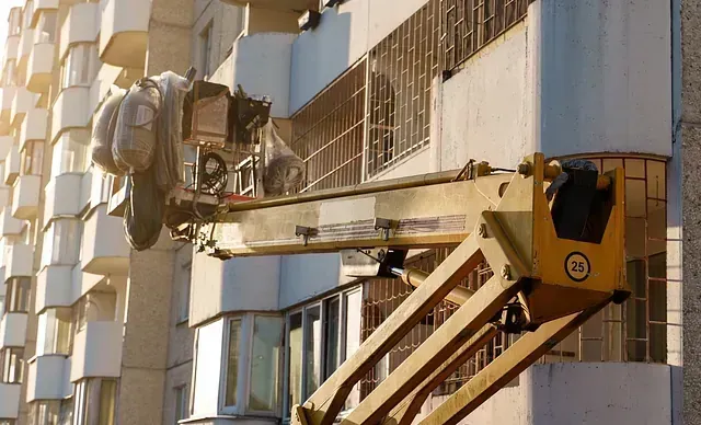Un hombre está trabajando en el lateral de un edificio con una grúa.