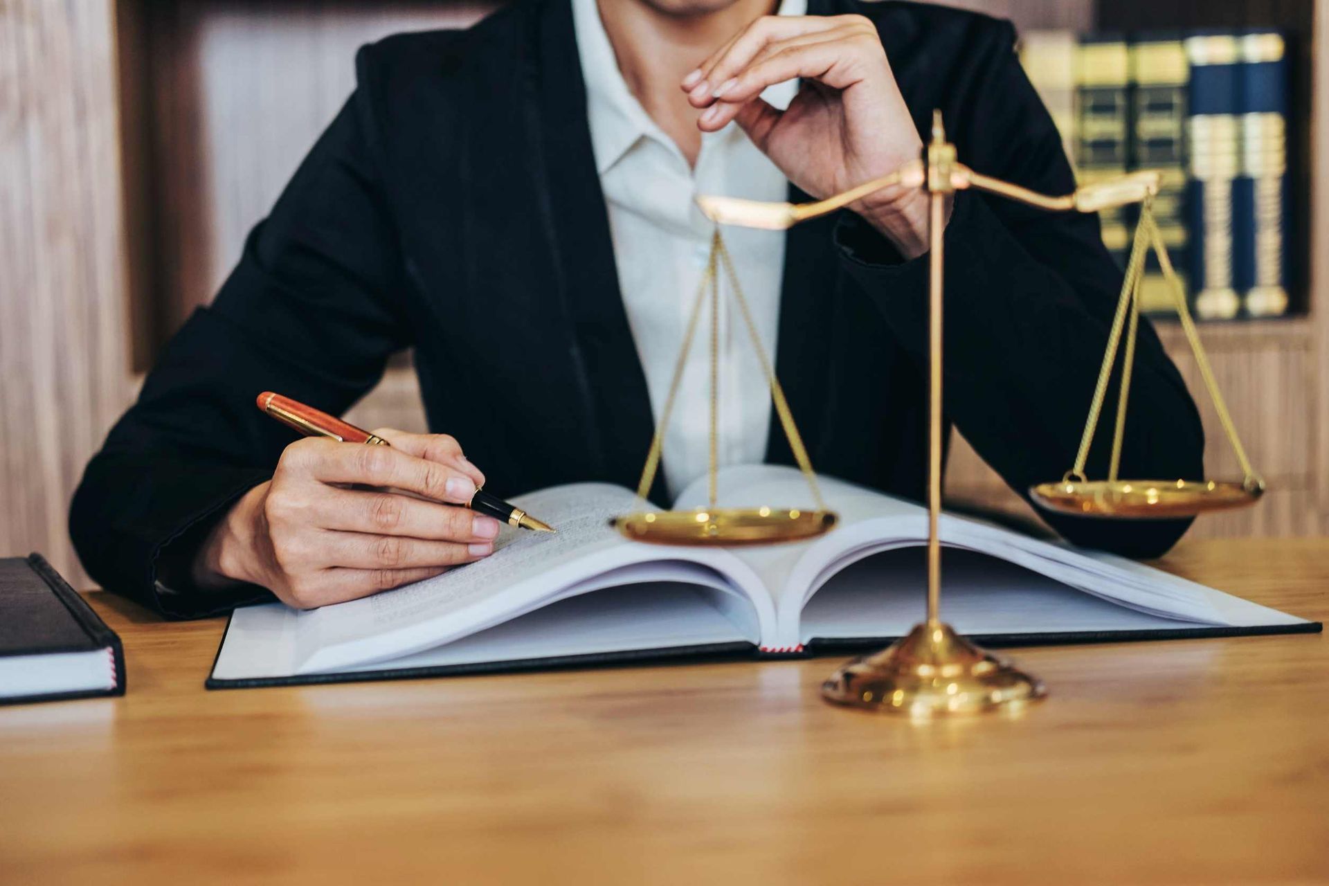 Un abogado está sentado en un escritorio con un libro y una balanza de justicia.