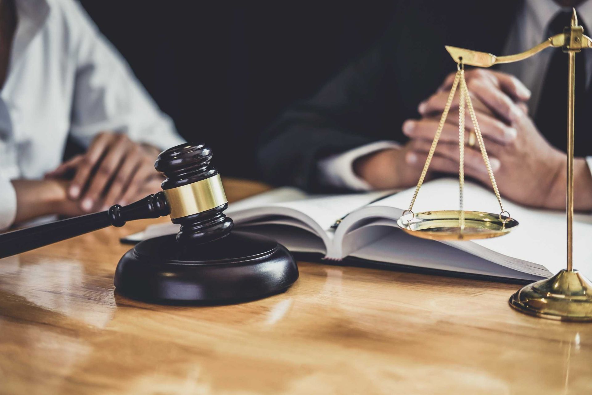 El mazo de un juez y la balanza de la justicia están sobre una mesa de madera.