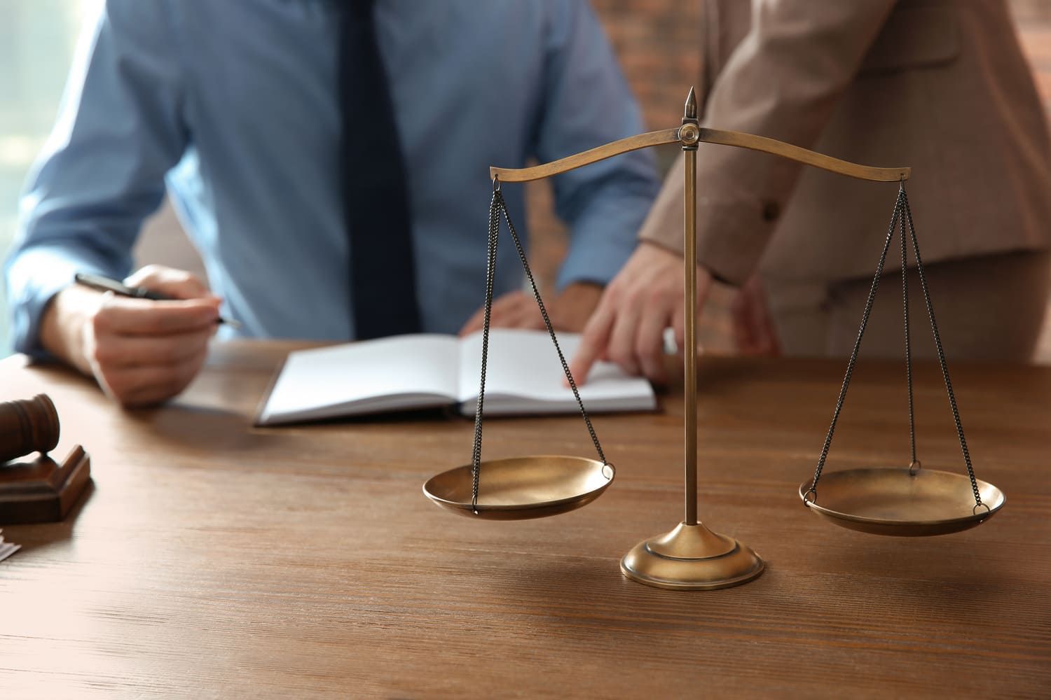 Un hombre y una mujer están sentados en una mesa con una balanza de justicia sobre ella.