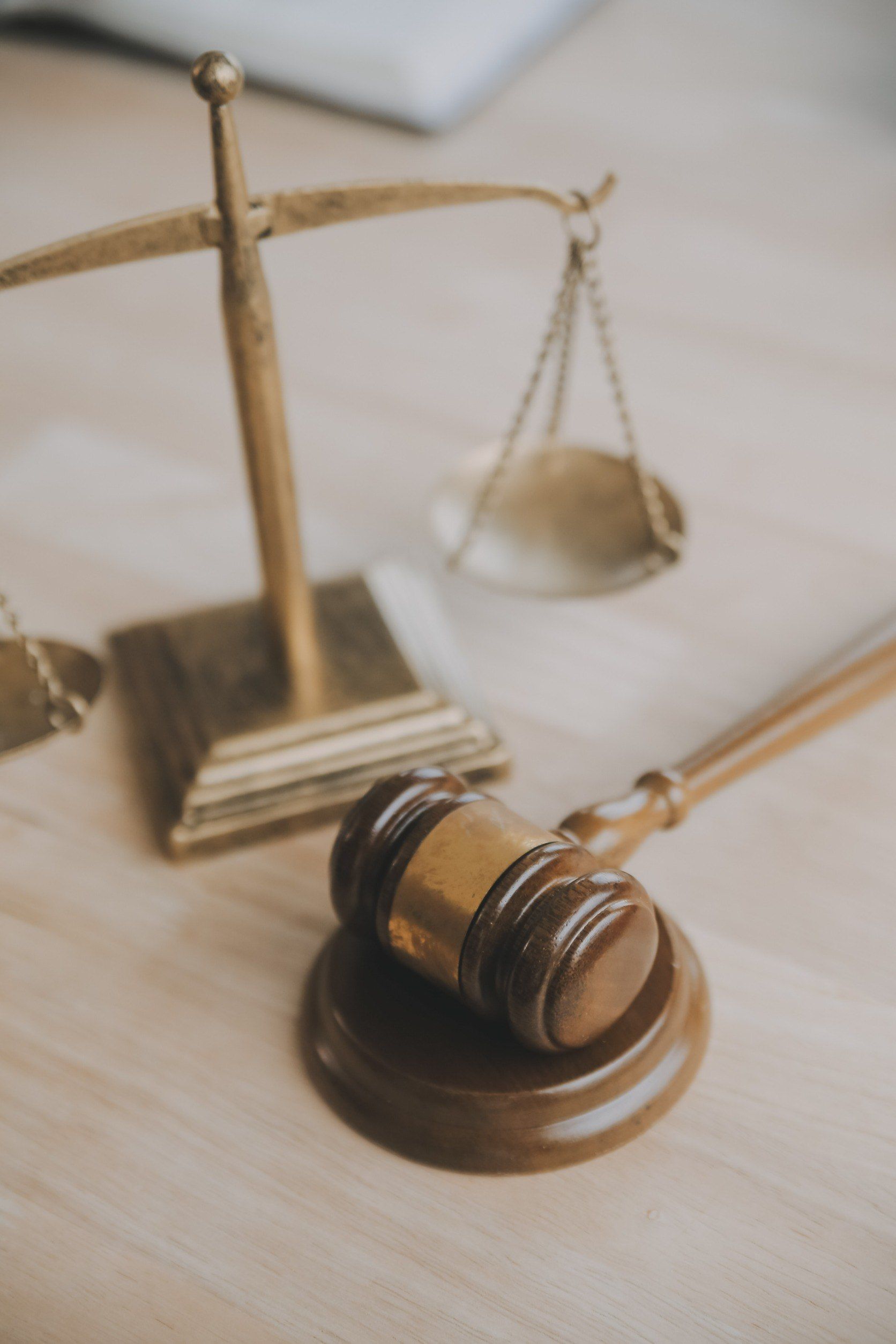 Un mazo de madera y una balanza de la justicia están sobre una mesa de madera.