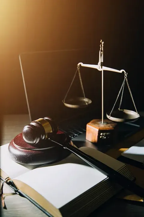 Sobre una mesa hay un mazo de juez, una balanza de la justicia y un libro.