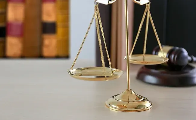 Una balanza de la justicia está sentada sobre una mesa al lado de un mazo.