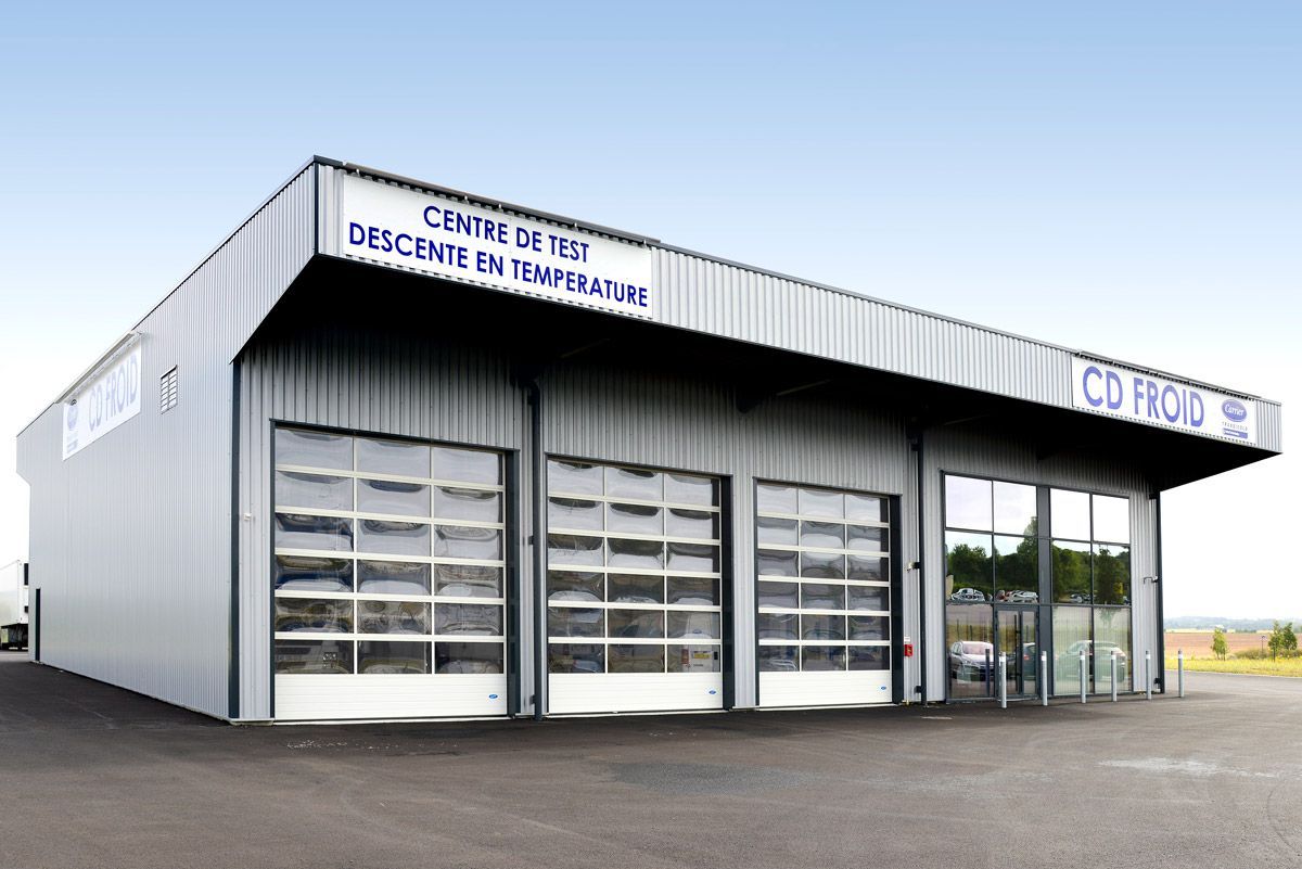Bâtiment moderne de lavage de voitures blanc avec baies de garage vitrées et signalétique bleue