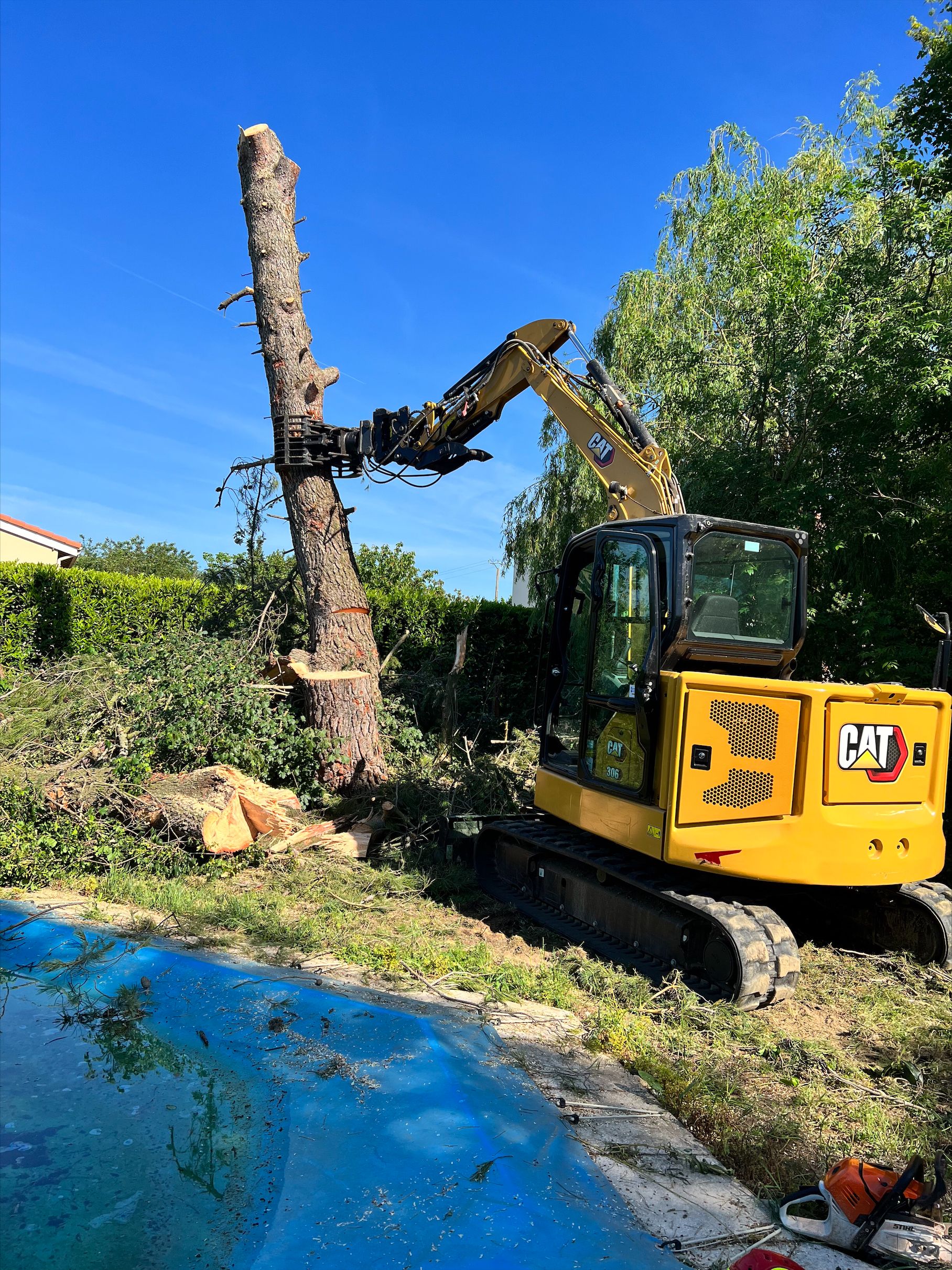 Un tractopelle jaune équipé d'un bras raboteur pour arbre.
