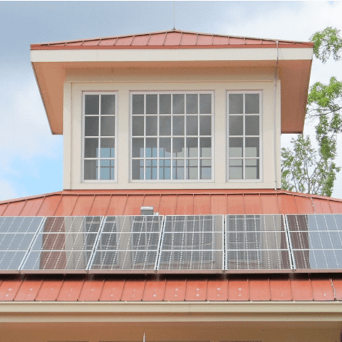 Ein Haus mit einem roten Dach und Solarzellen darauf