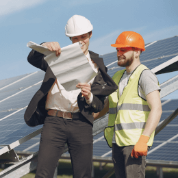 Zwei Männer stehen nebeneinander vor einem Solarpanel.