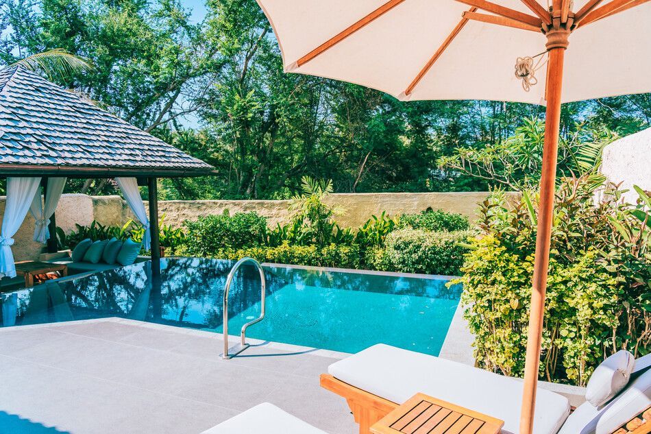 Una piscina con sombrillas y sillas alrededor.