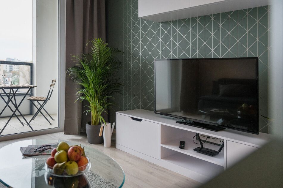 Una sala de estar con TV de pantalla plana y una mesa de café de cristal.