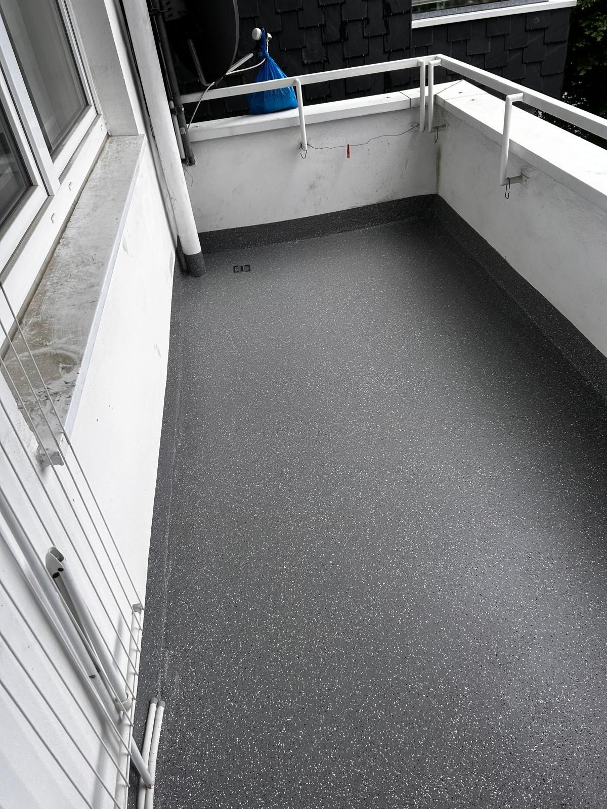 Grauer Balkon mit weißen Wänden und Geländer.