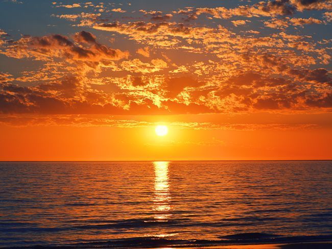 O sol está se pondo sobre o oceano e refletido na água.
