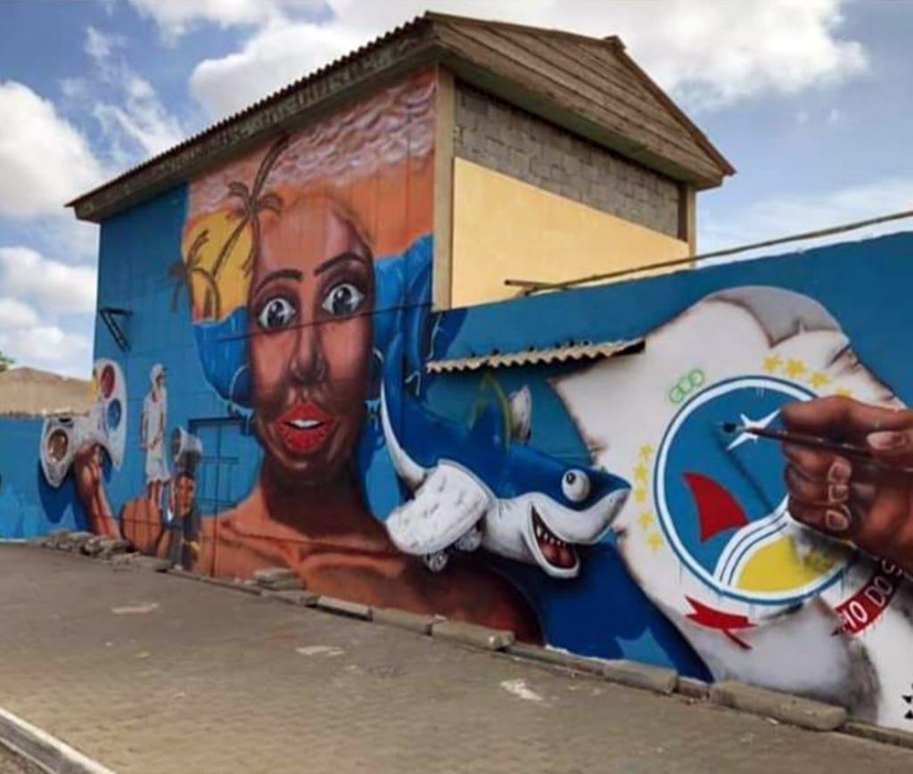 A mural on the side of a building shows a woman and a shark