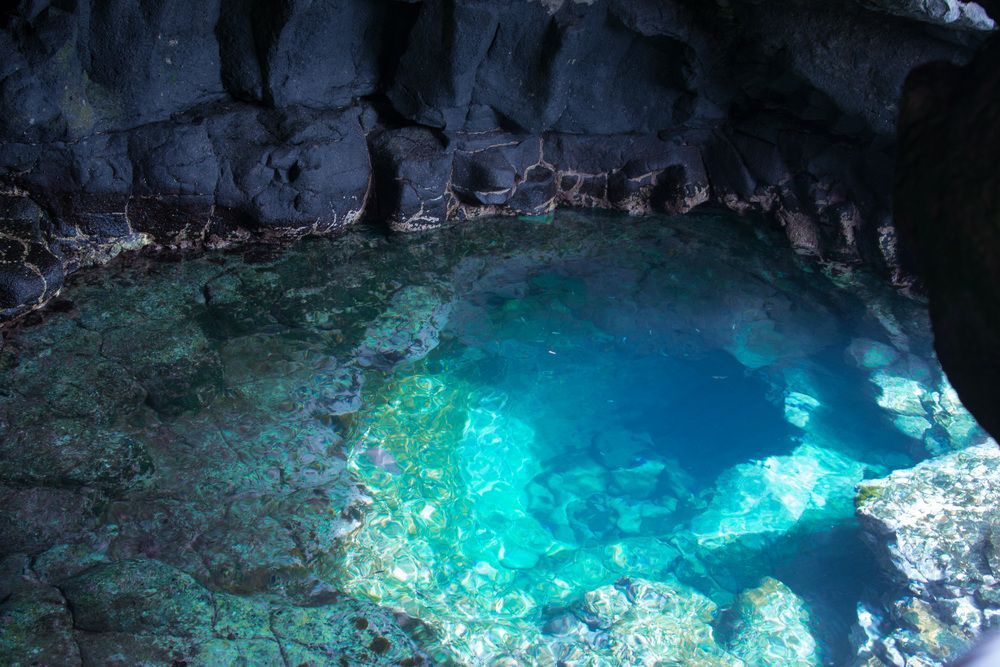 Uma caverna cheia de água azul-turquesa e pedras.