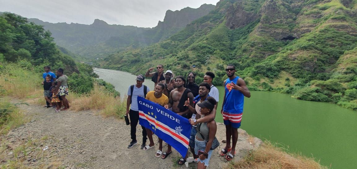 A group of people standing next to a river holding a flag.
