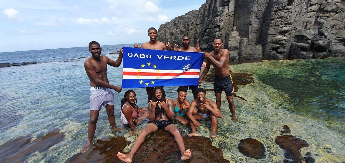 Um grupo de pessoas posa para uma foto enquanto segura uma bandeira.