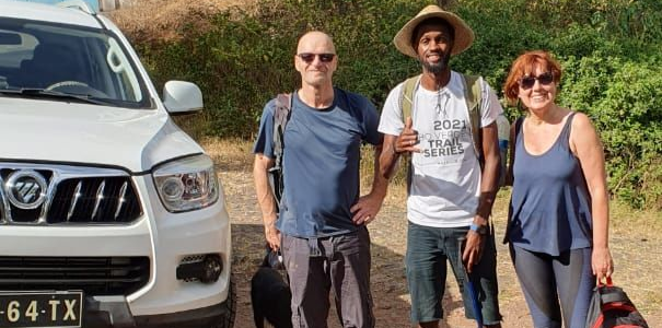 Três pessoas estão de pé perto de um SUV branco em um local ensolarado ao ar livre.
