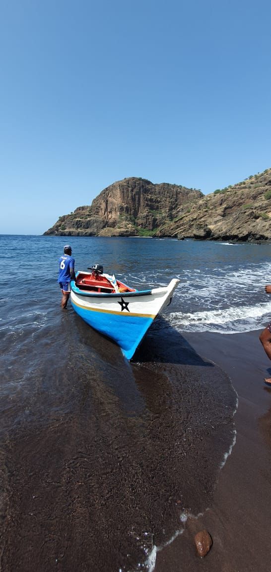 Um homem está tirando um barco da água em uma praia.