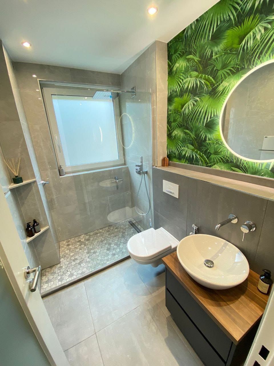 Modernes Badezimmer mit grauen Fliesen, Glasdusche und tropischer Tapete.