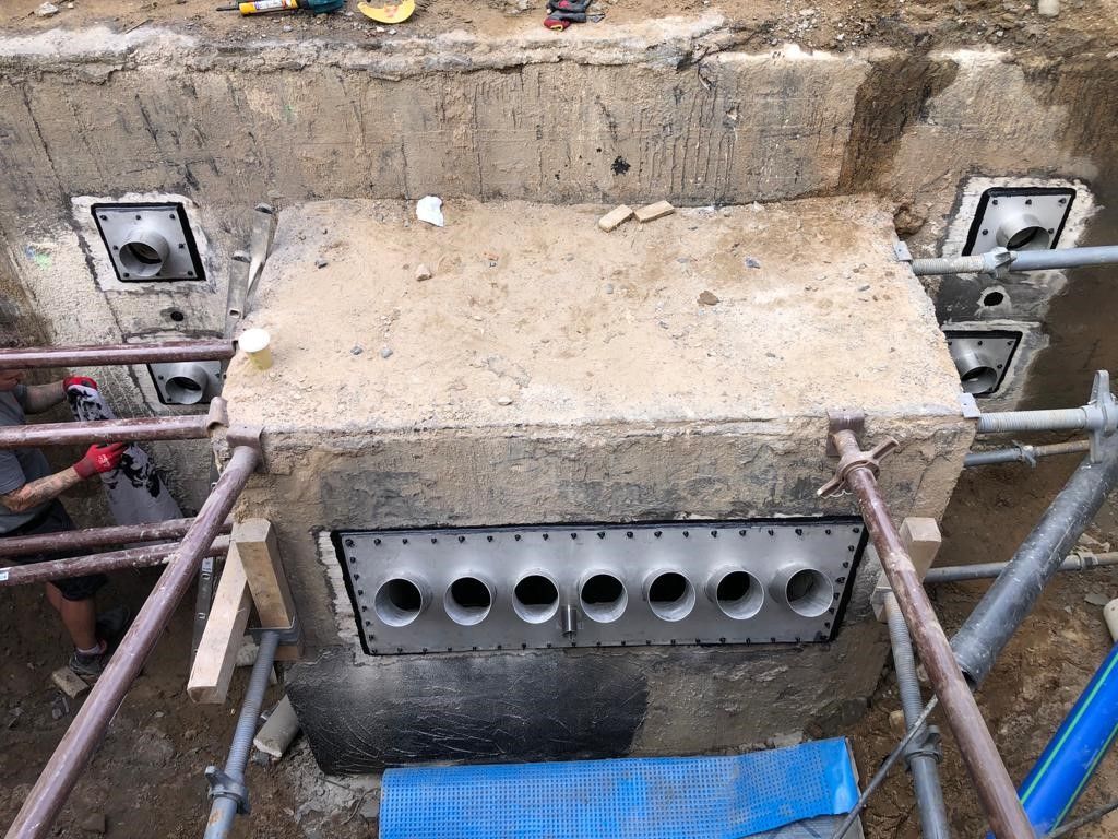 Ein Mann arbeitet in einem Loch im Boden an einer Betonkonstruktion.