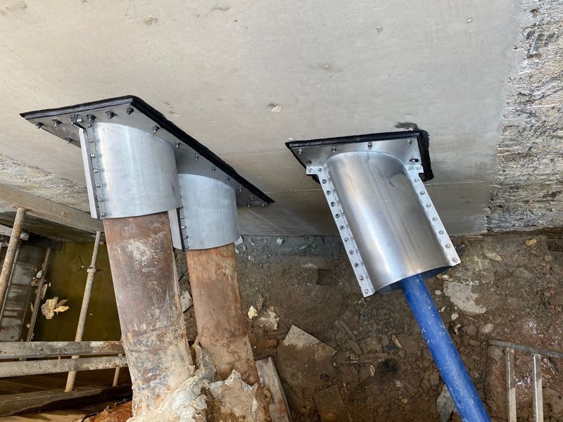 Zwei Metallrohre liegen auf einer Betonoberfläche.