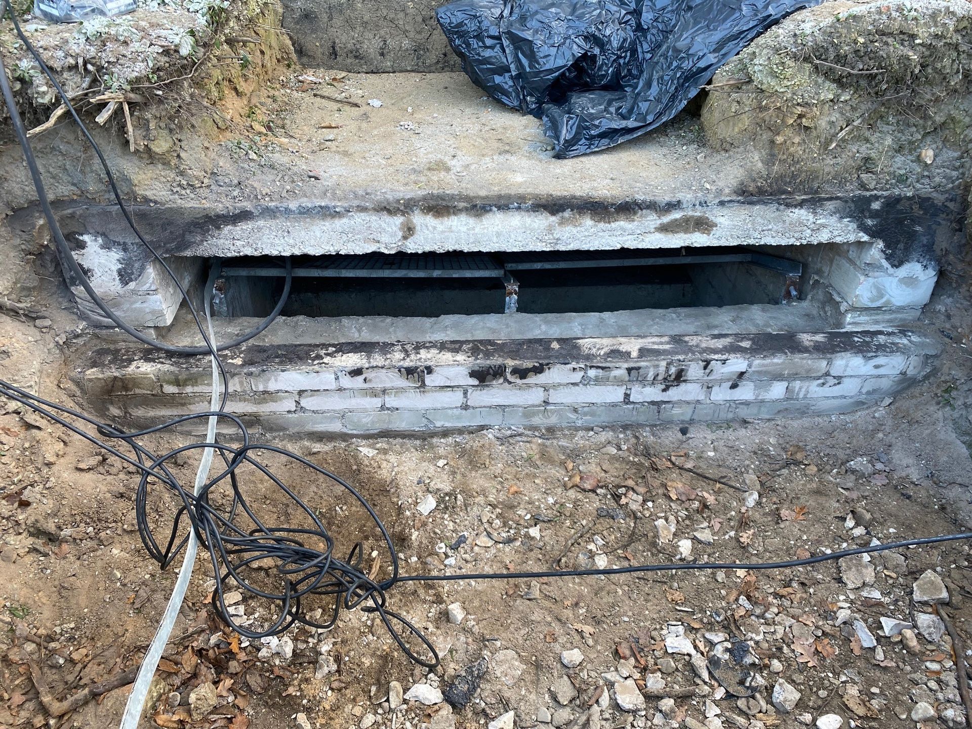 Eine Ziegelwand mit einem Loch darin und einem Haufen Kabel, die herauskommen.