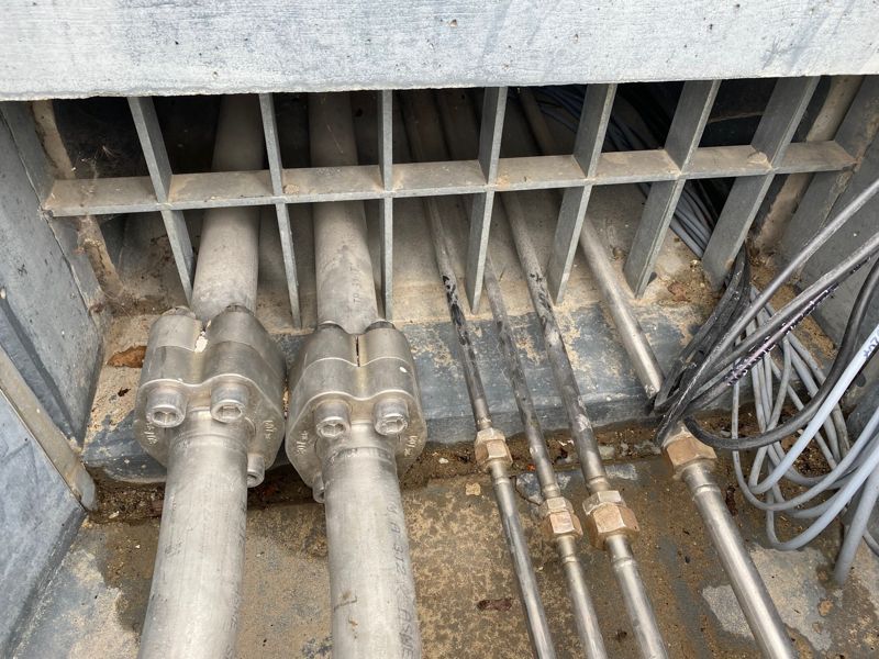 Aus einem Loch im Boden kommen mehrere Rohre.