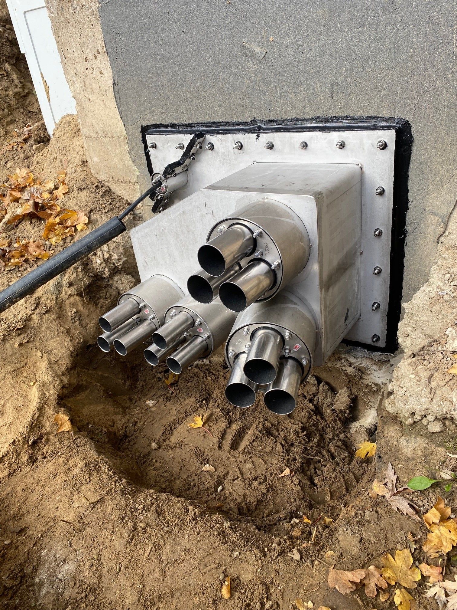 Aus einem Loch im Boden kommen mehrere Rohre.