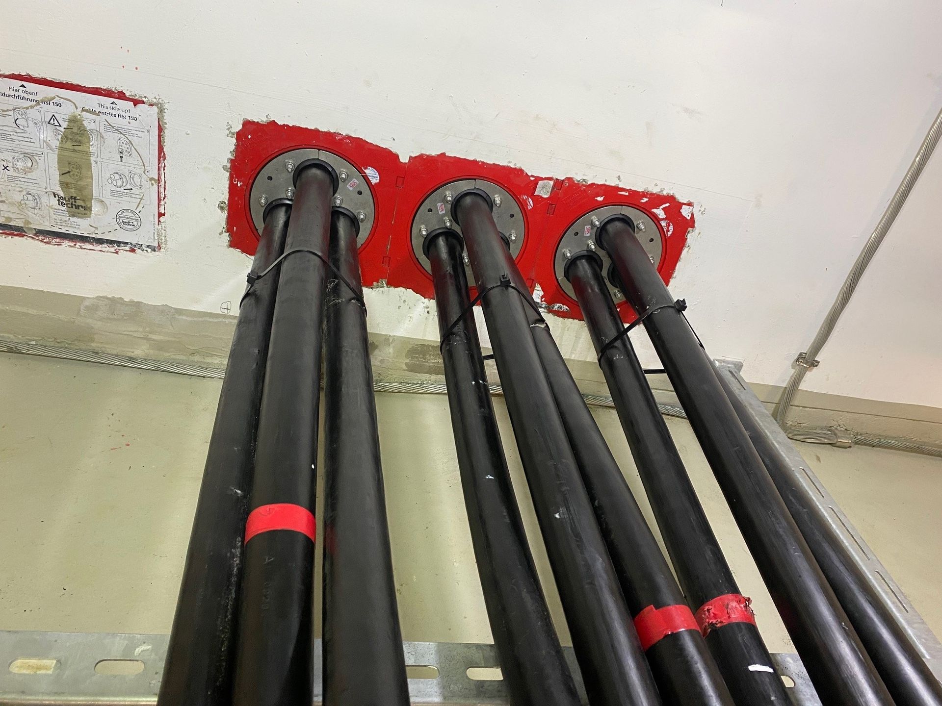 Ein Bündel schwarzer Rohre ist mit einer Wand verbunden