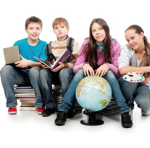Un grupo de niños está sentado sobre una pila de libros con un globo terráqueo delante de ellos.