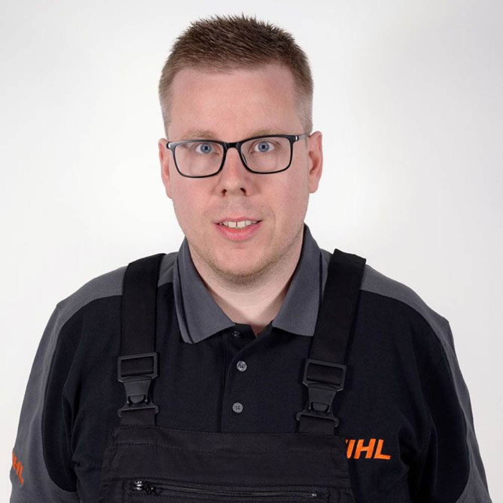 Mann mit Brille und dunkler Uniform mit STIHL-Logo schaut in die Kamera.