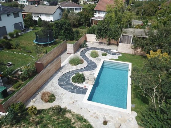 grosse Rasenfläche mit gepflasterten Wegen und einem Swimmingpool