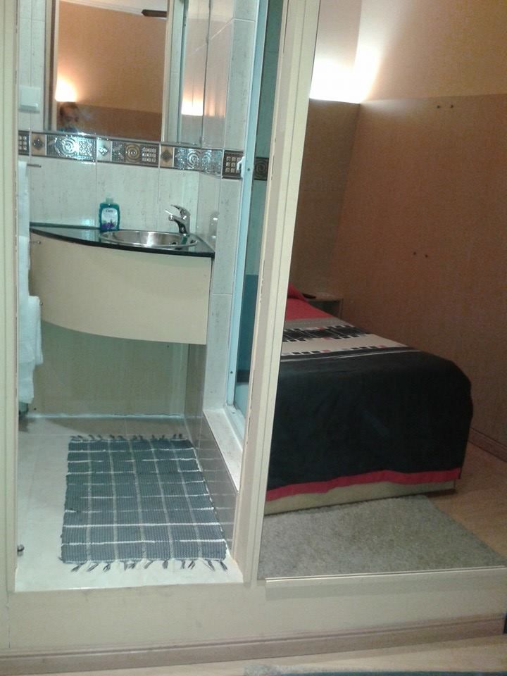 Um pequeno quarto com uma cama e uma área de banheiro com pia.