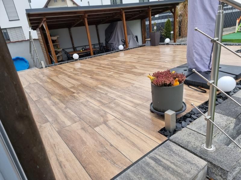 Holzterrasse im Garten mit überdachtem Sitzbereich und Pflanzkästen am Rand
