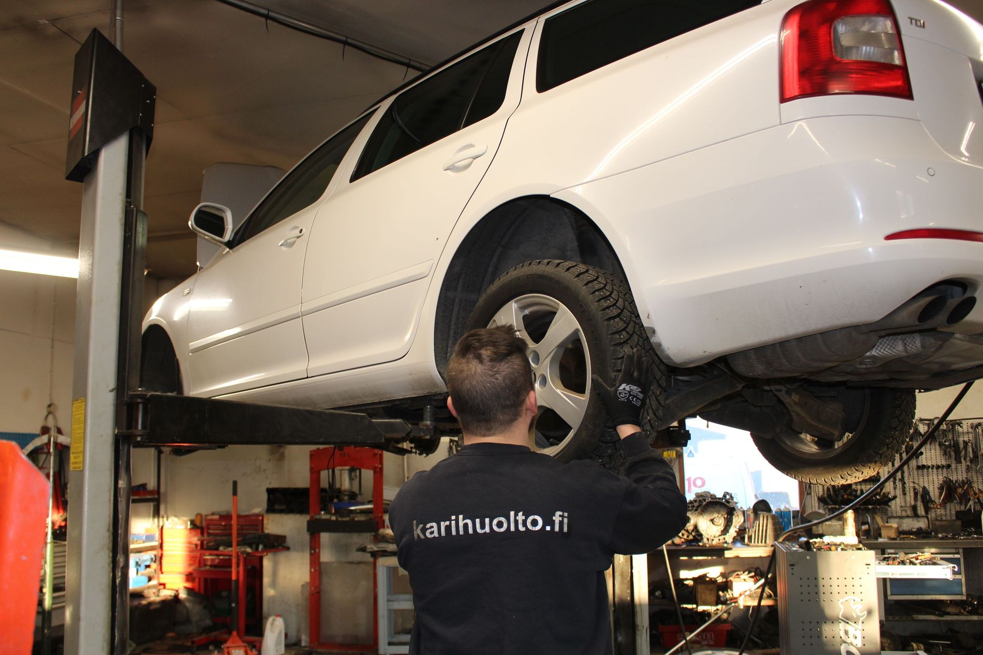 Mekaanikko tarkastaa valkoista autoa autokorjaamolla