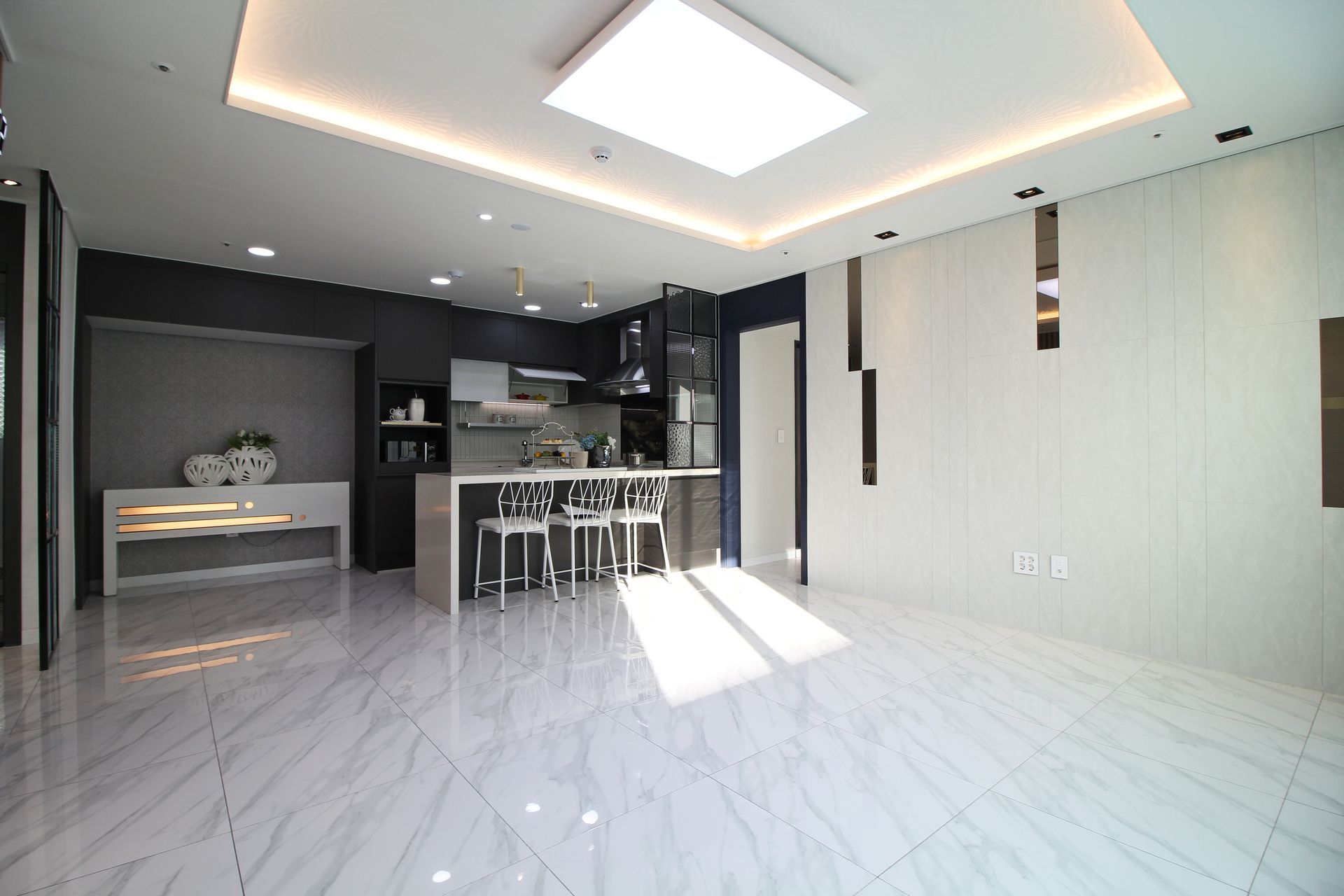 Cuisine et séjour modernes à aire ouverte avec sol en marbre blanc, appareils électroménagers intégrés et îlot central avec tabourets.