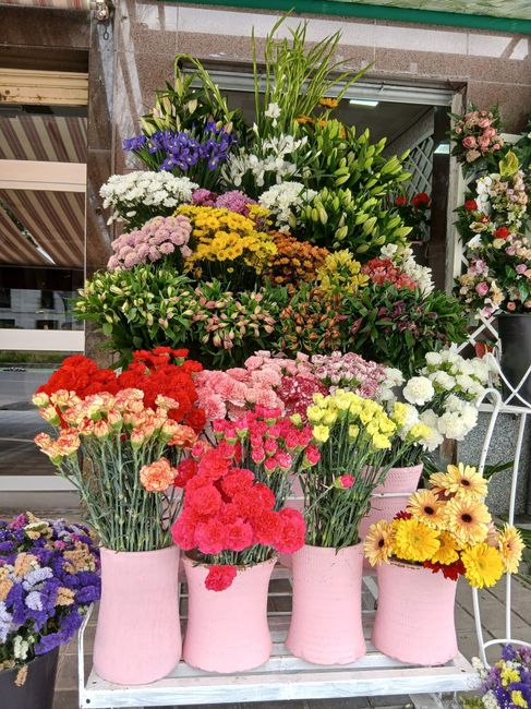 Colorido ramo de flores rojas, rosas, amarillas y blancas envuelto en papel rosa y verde con una cinta blanca.