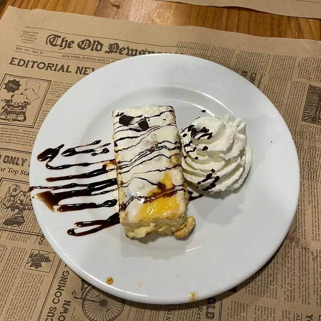 Un plato blanco con un trozo de pastel y crema batida encima.