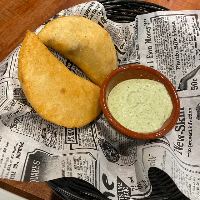 Un recipiente con salsa verde para mojar reposa sobre un trozo de periódico.