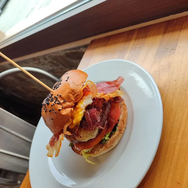 Un plato blanco con un sándwich encima y un palillo sobresaliendo de él.