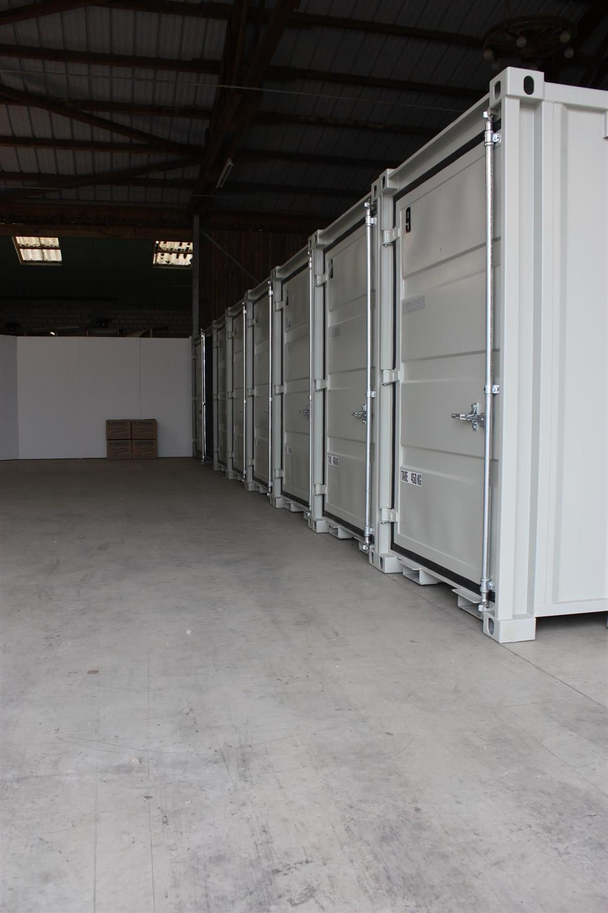 Eine Reihe weißer Container steht in einer Lagerhalle