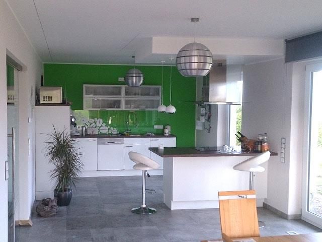 Eine Küche mit grüner Wand und weißen Schränken