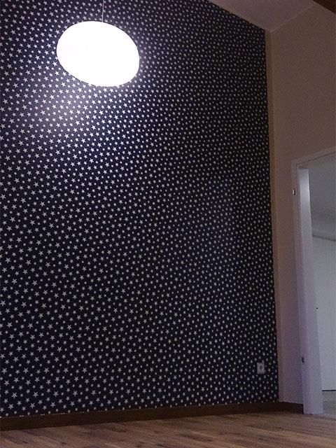 Ein Raum mit gepunkteter Tapete und einer Lampe an der Decke