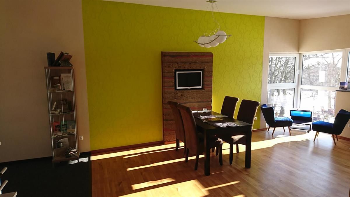 Ein Wohnzimmer mit einer gelben Wand und einem Tisch und Stühlen