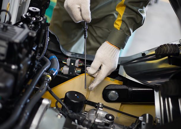 Ein Mann arbeitet mit einem Schraubenzieher an einem Automotor.