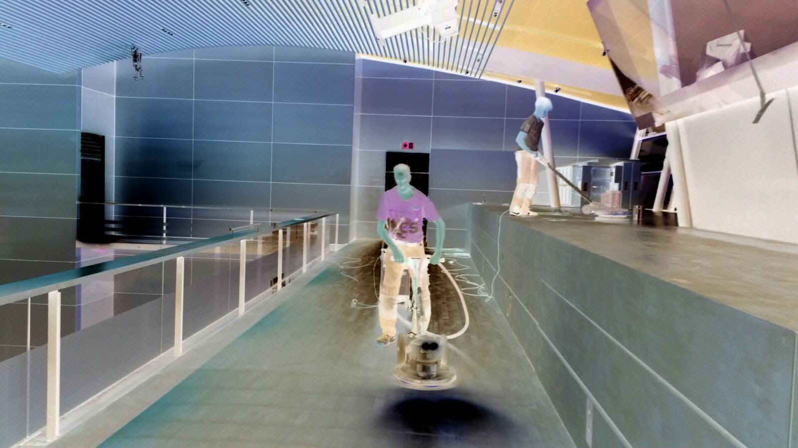 Person poliert einen Boden in einem Innenraum. Licht wird vom Boden reflektiert.