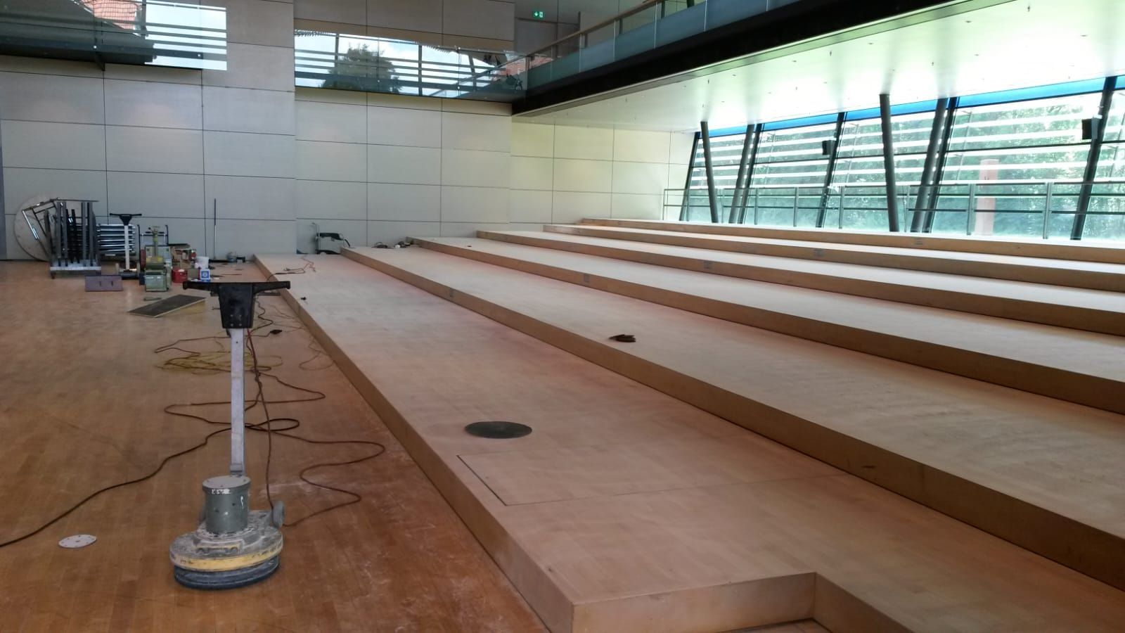 Im Bau befindlicher hölzerner Hörsaal; Bodenschleifmaschine, abgestufte Sitzplätze.