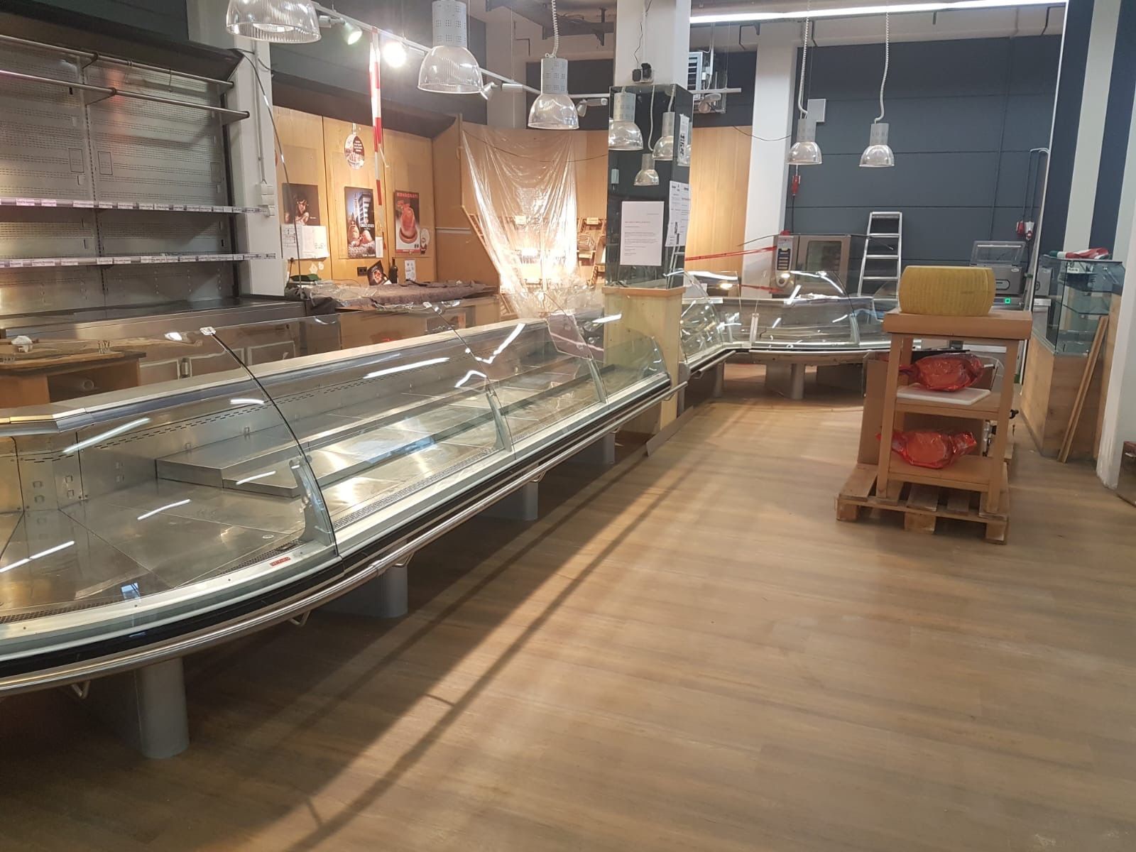 Leere Regale und Vitrinen im Lebensmittelgeschäft. Innenaufnahme mit Holzböden, Beleuchtung.